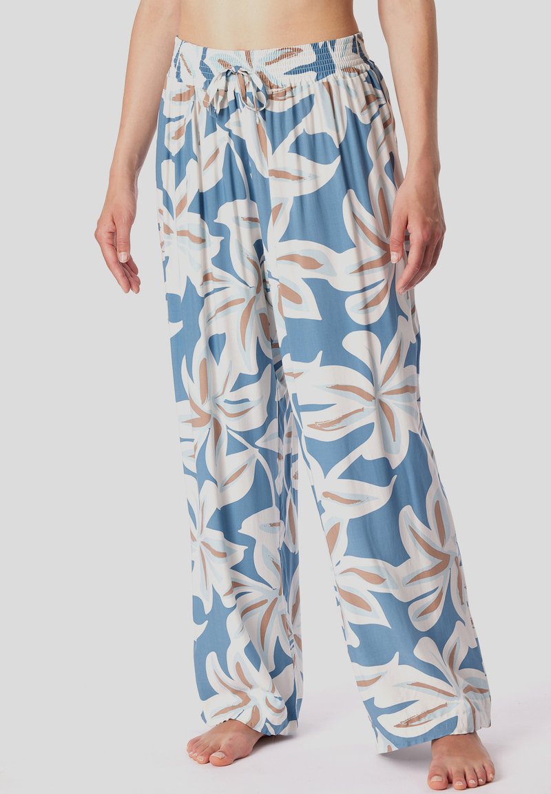 Pantaloni fluidi realizzati in tessuto leggero, con uno sfondo blu e grandi motivi floreali bianchi e beige, e una vita elastica.