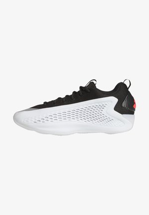 Chaussure de sport noire avec une tige texturée, une semelle intermédiaire blanche et des panneaux latéraux ventilés ; elle présente des lacets noirs et un accent rouge au niveau du talon.