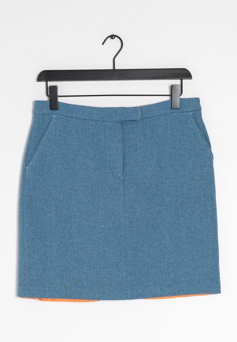 Mini falda texturizada azul con bolsillos laterales colgando de una percha negra, con un forro naranja ligeramente visible en el dobladillo inferior.