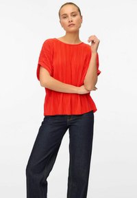 Rode geplooide blouse met korte mouwen, een ronde halslijn en een ontspannen pasvorm, gecombineerd met donkerblauwe denim broek.