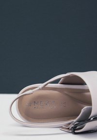 Lys rosa sandal med en glat overflade og åben design, med en tynd rem og trykt logo på indersålen.