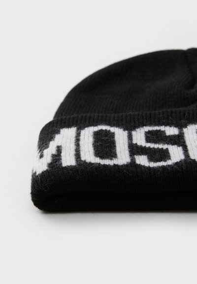 Musternoolitud must beanie, millel on volditud äär ja valged tähestikud. Tekstuur näeb välja pehme ja veidi uduselt, näidates lihtsat ja juhuslikku disaini.