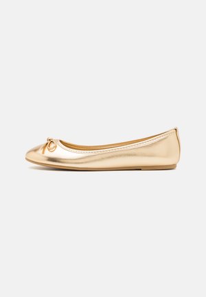 Ballerines métalliques dorées avec un bout arrondi, petit nœud décoratif à l'avant, surface lisse et semelle en caoutchouc flexible.