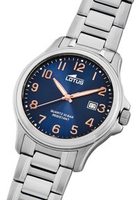 Montre en acier inoxydable argenté avec un cadran bleu marine, des index des heures en or rose et un affichage de la date. Elle dispose d'un mouvement à quartz et d'une résistance à l'eau de 10 bars.