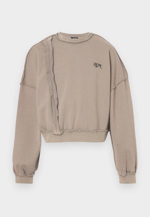 Nobružs bēšs sporta krekls ar safrēzētām malām, pārspīlētiem piedurkņu galiem un melnu logo "ADR" uz krūtīm. Mīksta auduma tekstūra un brīvs piegriezums.