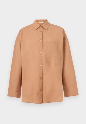 Beige langärmliges Hemd mit Knöpfen, Kragen und einer einzelnen Brusttasche, vor einem schlichten hellen Hintergrund dargestellt.