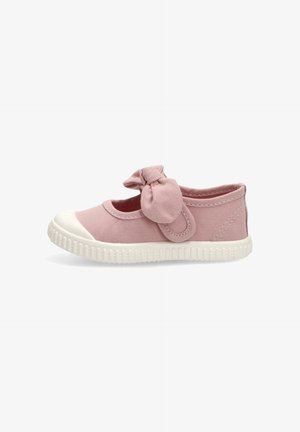 Zapatilla para niño pequeña de lona rosa con suela y puntera de goma blanca, con una correa de tela que lleva un lazo adjunto en el lateral.