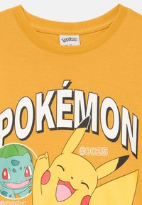 Gelbes Baumwoll-T-Shirt mit großem schwarzen "POKéMON"-Text und Grafikdrucks von Pikachu und Bisasam mit entsprechenden Zahlen.