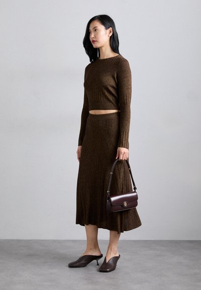 Set din tricot maro cu dungi, format dintr-un top scurt și o fustă lungă. Accesorizat cu o geantă bordeaux și mule cu toc maro.