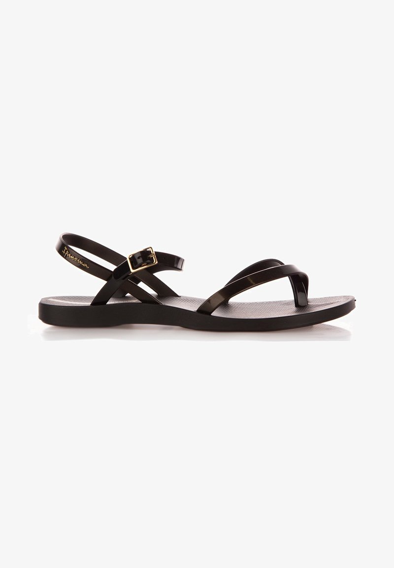 Czarne płaskie sandały z teksturowaną wkładką, z cienkimi, błyszczącymi paskami i małym akcentem w postaci klamerki. Prosty i minimalistyczny design.