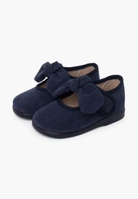 Scarpe in suede blu navy con un morbido dettaglio a fiocco su ciascun superiore, punte arrotondate e una suola nera flessibile. Texture liscia con bordi cuciti.