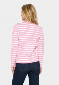 Haut à manches longues avec des rayures horizontales roses et blanches, décolleté rond, en doux coton, associé à un jean en denim foncé.