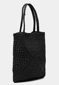 Černá taška přes rameno vyrobená z pleteného materiálu, s texturovaným povrchem a geometrickým vzorem, a dvěma splétanými uchy pro lepší úchop.