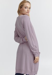 Robe pull en lilas tricotée, à manches longues, avec des poignets côtelés et une coupe décontractée, arborant un motif légèrement texturé et des poches latérales.