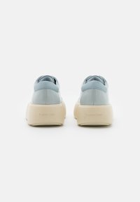 Baskets en cuir bleu avec une semelle épaisse crème, présentant une forme arrondie et un logo discret Calvin Klein sur le talon.