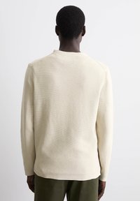 Helles beige Langarm-Sweatshirt mit strukturiertem Strickmuster, Rundhalsausschnitt und lockerer Passform, mit gerippten Bündchen und Saum.
