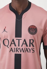 Muž v růžovém a černém fotbalovém dresu Paris Saint-Germain se znakem Qatar Airways a symbolem značky Jordan.
