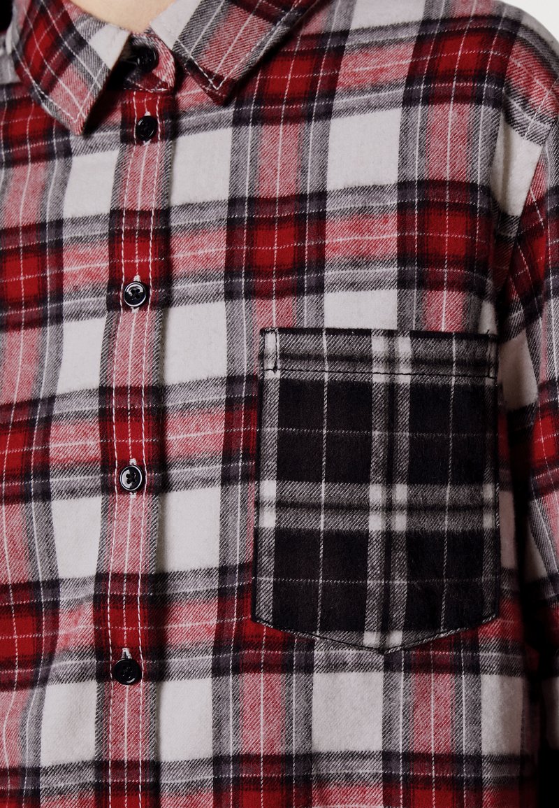 Czerwona i czarna koszula flanelowa w kratę z małą czarną kieszonką na piersi, z kołnierzykiem na guziki i czarnymi guzikami. Miękka tekstura.