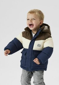 Cappotto imbottito in marrone, crema e blu navy con cappuccio. Presenta due tasche frontali, chiusura con bottoni e una fodera morbida. Adatto per bambini.