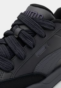 Zwarte leren sneaker met een gestructureerde oppervlakte, dikke donkere veters, verstevigde neus en een reliëflogo aan de zijkant. Modern ontwerp en gestroomlijnde vorm.
