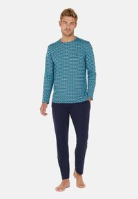 Langärmliges Oberteil in Blau mit geometrischem Muster, kombiniert mit marineblauen Hosen. Beide Teile haben eine lockere Passform und eine weiche Textur, die sie ideal für Loungewear machen.