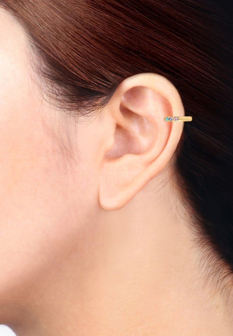 Pendiente de aro de oro con un diseño delgado, que presenta una pequeña sección adornada con gemas de colores. Llevado en el lóbulo de una oreja humana.