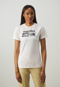 Balta medvilnės marškinėliai trumpomis rankovėmis su juodu grafiniu dizainu, kuriame spausdinamas tekstas "The North Face" ir koordinatės priekyje. Apvalus kaklas.