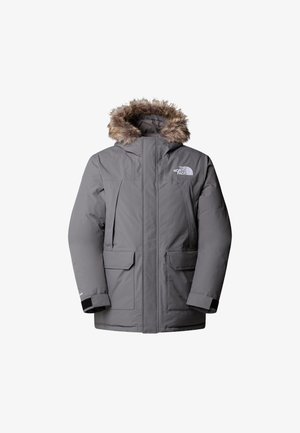 Parka isolée grise avec capuche en fourrure, deux poches avant et fermeture éclair. Présente un logo de marque sur la poitrine et des accents noirs.