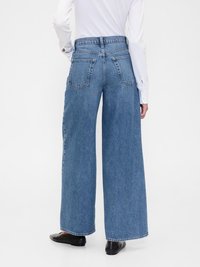 Jeans a gamba larga in denim azzurro chiaro, con vita alta, due tasche posteriori e una finitura pulita. Le gambe sono lunghe fino a terra e dritte.