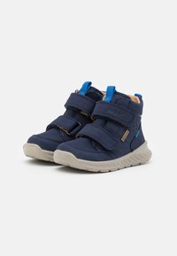 Dunkelblaue Kinderschuhe mit zwei Klettverschlüssen, beigen Gummisohlen, verstärkten Zehenkappen und einem strukturierten Design im Obermaterial.