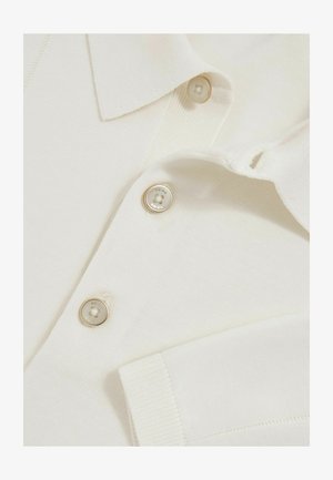 Weißes Baumwoll-Polohemd mit einem Kragen, zwei glänzenden Knöpfen und gerippten Bündchen. Strukturierter Stoff mit einem dezenten Strickmuster.