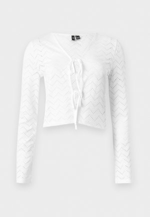 Hvit cropped topp med lange ermer, hullmønster i sikksakk og knyting foran, V-utringning og tettsittende silhuett.