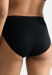 Schwarze Baumwollunterwäsche mit hoher Taille und glatter Textur, ausgestattet mit einem gezackten Rand und nahtlosen Seiten für eine enge Passform.