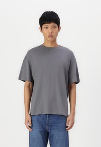 Grå oversize t-shirt i mjukt tyg med rund halsringning, korta ärmar och rak fåll. Bärs med blå jeans.