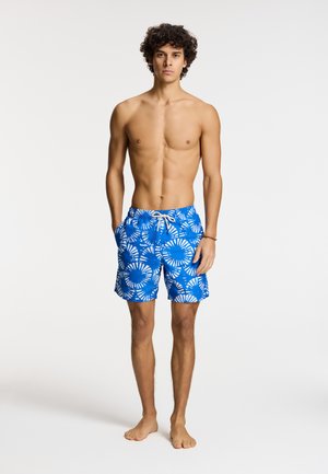 Costumi da bagno blu con motivo a spirale bianco, vita regolabile con cordoncino e tasche laterali. Tessuto leggero, design lungo fino al ginocchio, adatto per la spiaggia.