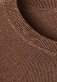 Gros plan d'un col de pull marron tricoté avec une texture côtelée visible et des détails fins du tissu tricoté.