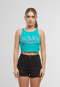 Mėlynas atviras tank topas su purpurine apdaila ir priekine spauda "Von Dutch ORIGINALS"; derinamas su juodais džinsinės šortais su plaukeliais.