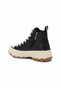 Zapatillas altas negras con acabado texturizado, cordones color crema, cremallera lateral y suela de goma gruesa en blanco y marrón.