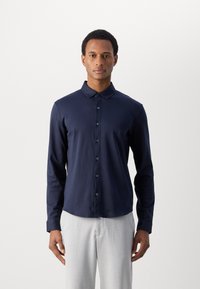 Polo a maniche lunghe blu navy realizzato in tessuto misto cotone, con chiusura a bottoni, colletto e dettagli di cucitura discreti.