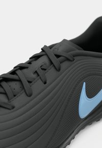 Μαύρο αθλητικό παπούτσι με υφή στο επάνω μέρος, κυρτή σχεδίαση, μπλε λογότυπο και μαύρα κορδόνια που ταιριάζουν. Διαθέτει τρύπες για αναπνευστικότητα.