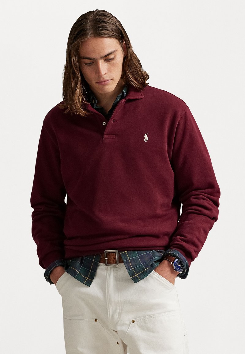 Polo à manches longues bordeaux en mélange de coton, avec un col classique et un logo brodé sur la poitrine, superposé sur une chemise à carreaux.
