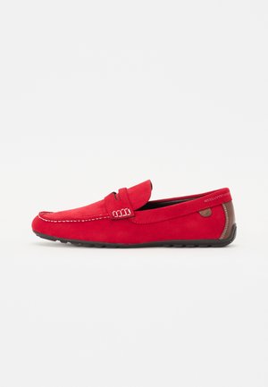 Red suede loafers with a stitched accent, rubber sole, and a brown heel detail. Features a round toe and slip-on design.