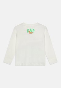Witte longsleeve shirt met een groen "GAP" logo en een croissantafbeelding op de rug. Gemaakt van zachte katoen.
