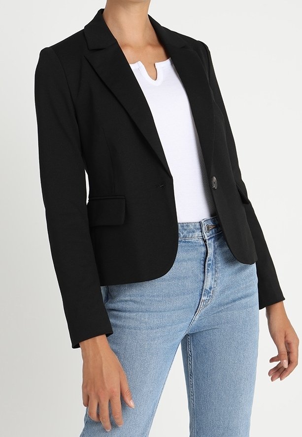 Schwarze taillierte Blazerjacke mit strukturiertem Design, einreihiger Knopfverschluss und zwei Fronttaschen, getragen über einem weißen Oberteil und blauen Jeans.