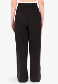 Pantaloni neri a gamba larga con vita alta e design plissettato. Realizzati in un tessuto morbido, presentano una vestibilità ampia e discrete tasche laterali.