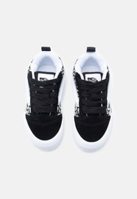 Ανδρικά αθλητικά παπούτσια σε ασπρόμαυρο χρώμα με υφή σουέντ μαύρο κάλυμμα στα δάχτυλα, λευκή λαστιχένια σόλα, μαύρα κορδόνια και λεπτομέρεια με λεοπάρ σχέδιο στα πλευρά.