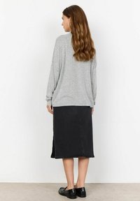 Light grey oversized sweater, black denim midi skirt with side slit, and black flat shoes. Textured fabric with casual fit and simple design.