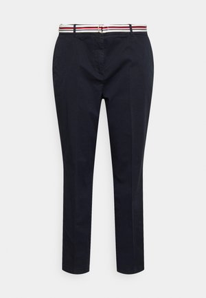 Pantalones ajustados azul marino con bolsillos frontales, trabillas para cinturón y un cinturón blanco con rayas rojas y azul marino y una hebilla plateada.