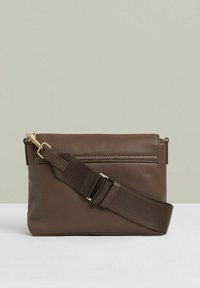 Brun læder crossbody taske med en glat overflade, justerbar stofrem og lynlåslukning. Har en forsyet detalje foran og hardware i guld tone.