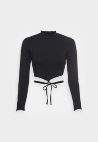 Mustapituinen, pitkähihainen, lyhyt toppi, joka on valmistettu joustavasta materiaalista. Siinä on korkea kaula-aukko ja solmikohta vyötäröllä, ja se sisältää aukollisen muotoilun.